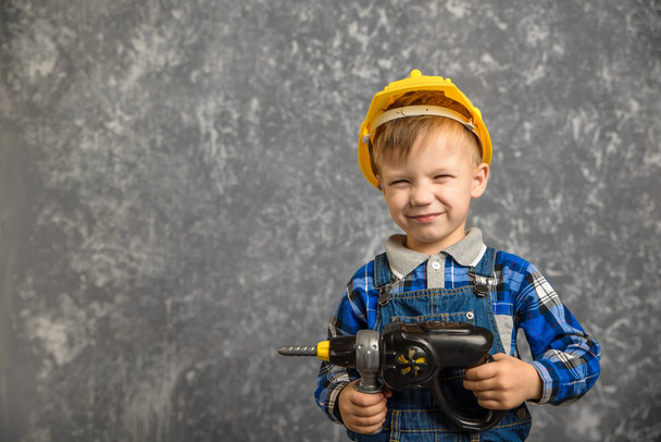 Boy in hard hat with drill, screwdriver in hand - Фото, изображение