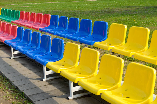 2 つの行に立ってスポーツのファンのための色とりどりのベンチ. - 写真・画像
