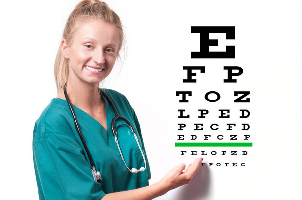 Young female doctor on eyesight test chart background. - Fotoğraf, Görsel