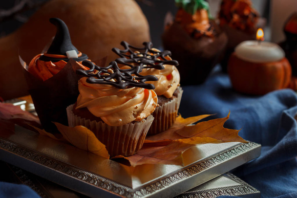 Halloween Cucpcakes with text topper decoration and orange cream. Candles and pumpkin background - Φωτογραφία, εικόνα