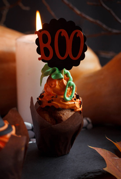 Halloween Cucpcakes with text topper decoration and orange cream. Candles and pumpkin background - Fotó, kép