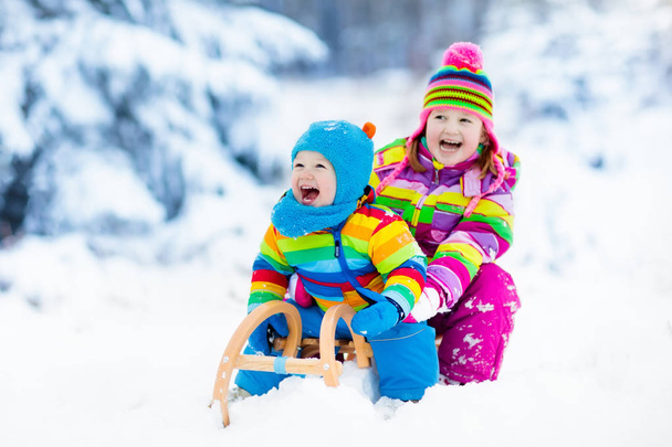 Kids on sleigh ride. Children sledding. Winter snow fun. - Zdjęcie, obraz