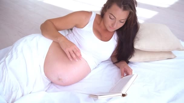 妊娠中の女性は、ベッドの読書本出産にあります。 - 映像、動画