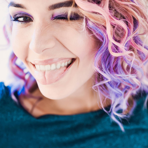 close-up portrait in studio isolated beautiful sexy young blond hipster girl with lilac and pink hair posing with tooth smile - Photo, Image