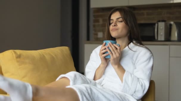 Woman Enjoys Coffee in Armchair - Filmati, video