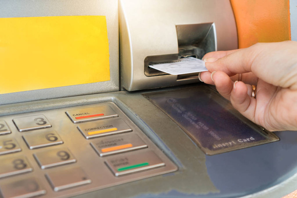 Рука вставляє банкоматну картку в банківську машину
. - Фото, зображення