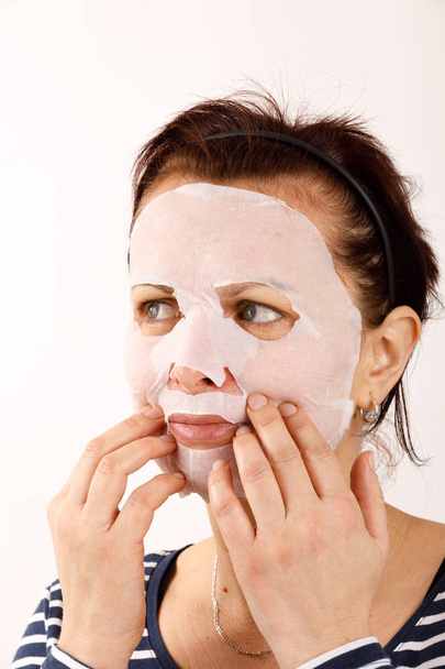 γυναίκα νοικοκυρά με φύλλο μάσκα στο πρόσωπό της - Φωτογραφία, εικόνα