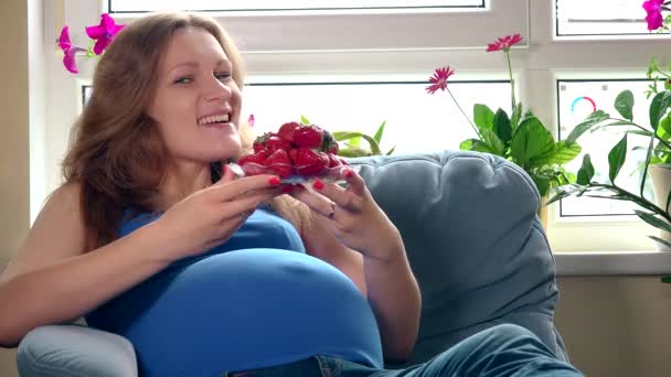 Szép terhes nő eszik szamóca, és mosolyogva néztem kamera - Felvétel, videó