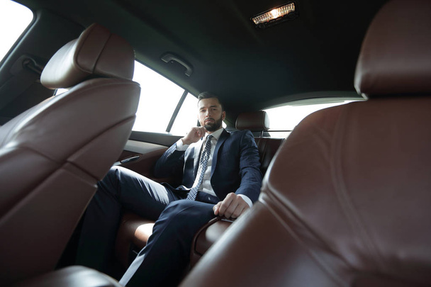 businessman talking on the phone while sitting in the back seat of his car - Foto, Bild