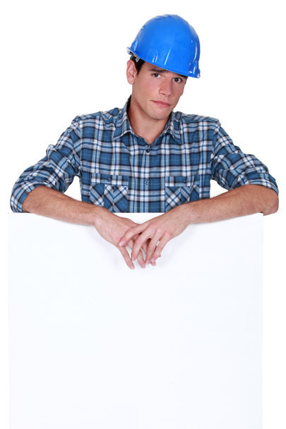 Downbeat manual worker stood with blank poster - Photo, image