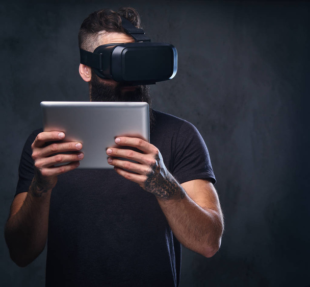 Un uomo che indossa occhiali VR e tiene tablet PC
. - Foto, immagini