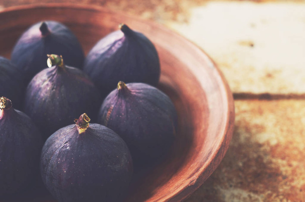 Ripe figs in clay bowl on grunge metal background - 写真・画像