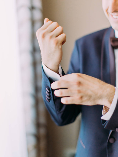 Close-up view of the hand of the groom buttoning the wedding jacket. - Foto, Imagen