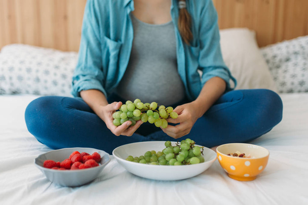 pregnant woman eating grapes - Фото, изображение