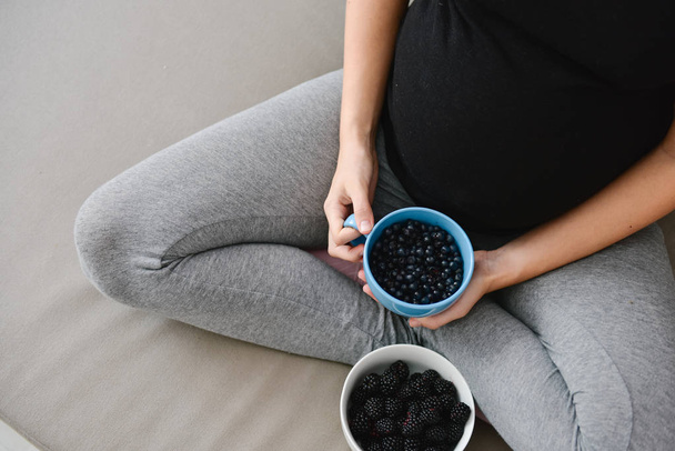 pregnant woman eating blueberries and blackberries  - Photo, Image