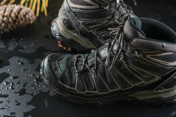 Black hiking boots, wet by a puddle of water - Foto, afbeelding