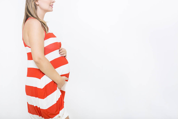 Jovem mulher grávida muito sorridente no fundo branco
 - Foto, Imagem