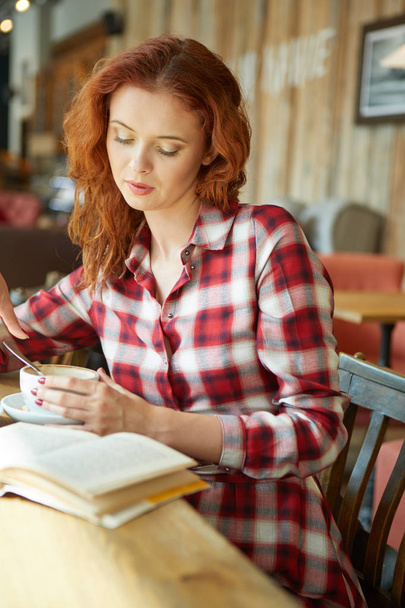 Red haired woman reading book  in cafe. City break  concept - Photo, Image