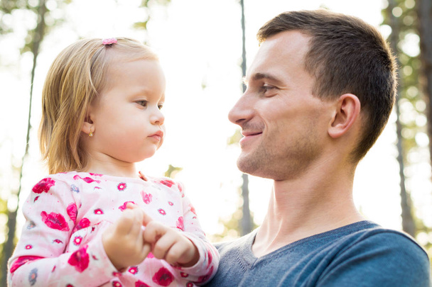 Young father holding cute toddler girl daughter in his arm, smiling and looking at her - Foto, imagen