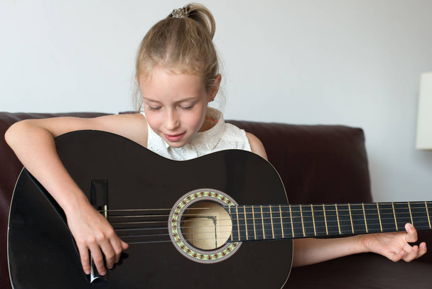 Little girl learns to play guitar. - 写真・画像