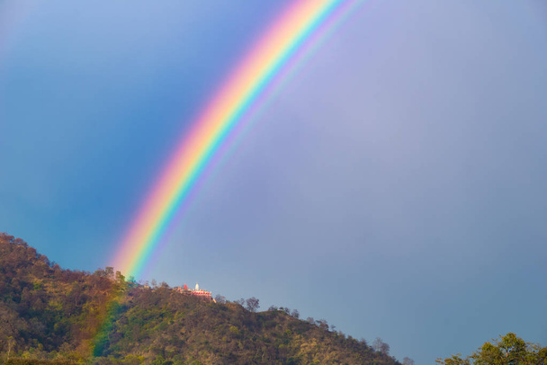 Colorful bright rainbow in the sky. Temple on the hill. - Photo, Image