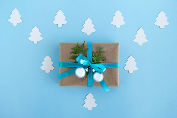 Lahjapakkaus kääritty veneet paperi, sininen nauha ja koristeltu kuusen oksat ja hopea Joulupallot sinisellä pohjalla valkoinen paperi kuusen, ylhäältä
. - Valokuva, kuva