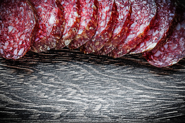 Sliced salami on wooden board - Foto, afbeelding