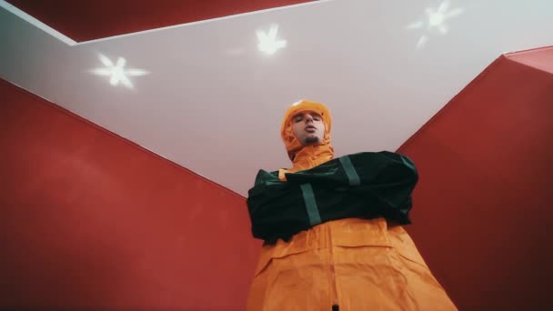 Homem em casaco de construtor e laranja chapéu duro cruz armada na sala vermelha, rap
 - Filmagem, Vídeo