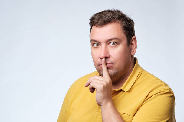 Finger on lips as man gesturing shh sign - Photo, Image