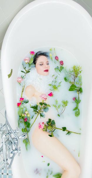 Mujer con flores de rosa en el baño de espuma
 - Foto, imagen