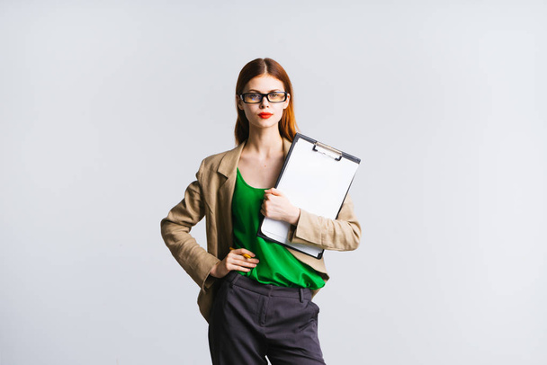 serious secretary girl holding herself at the waist with a file in her hand on a white background - Foto, Bild
