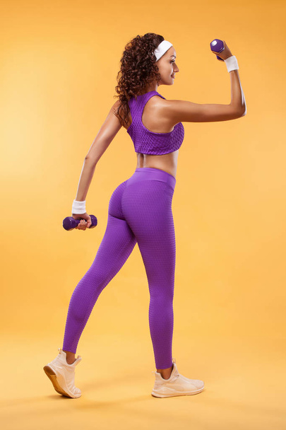 Sporty beautiful woman with dumbbells makes fitness exercising at white background to stay fit - Φωτογραφία, εικόνα