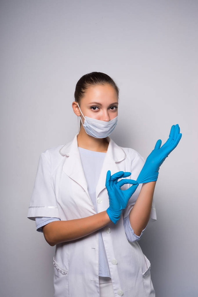 girl nurse with medical mask on face dresses on glove hand - Foto, Imagem