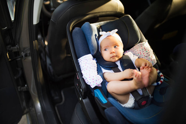 Little baby fastened with security belt in safety car seat. - Valokuva, kuva
