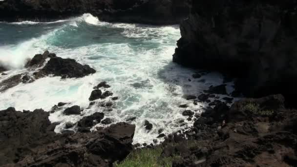 hillside view of waves crashing on rocks at sea cave - Footage, Video