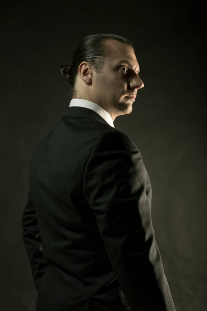 The attractive man in black suit on dark background - Photo, Image