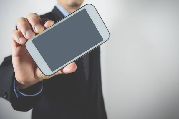 Close-up businessman holding smart phone. Businessman holding device screen mock up. - Foto, afbeelding
