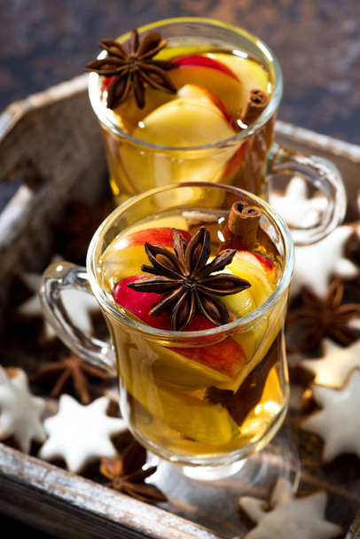 glass of spiced hot apple tea and gingerbread cookies, vertical - Фото, изображение