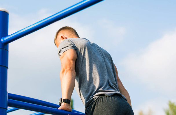 Man performing Russian pull ups on a workout outdoors - Photo, Image