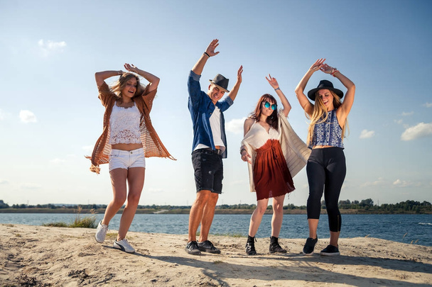 Groep vrienden feesten en dansen op het strand - Foto, afbeelding