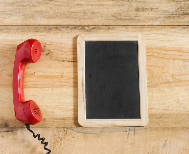 Rode oude ouderwetse telefoonhoorn op houten tafel - Foto, afbeelding