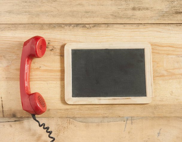 Червоний старомодний телефонний приймач на дерев'яному столі
 - Фото, зображення