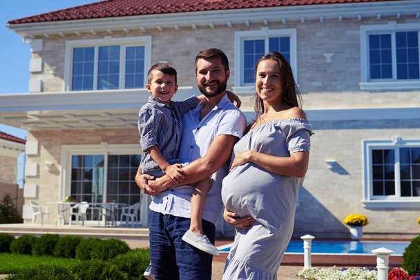 Happy family standing in front of new modern house - Photo, Image