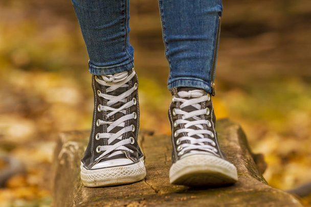 Κορίτσι που φοράει με μαύρα αθλητικά παπούτσια με τα πόδια σε ξύλο - Φωτογραφία, εικόνα