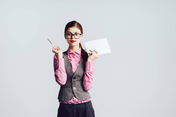 cute girl in a suit and a pink shirt holding a pen and paper - 写真・画像