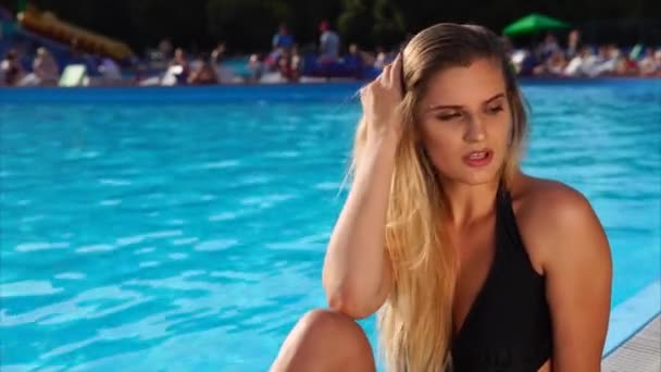 schlanke Mode Blondine sitzt an einem Pool-Rand bei sonnigem Tag im Freien. - Filmmaterial, Video