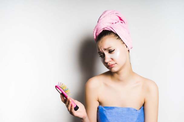 The girl in the towel looks sad at her multicolored comb - 写真・画像