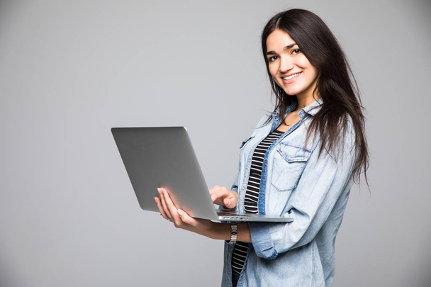 Ολόσωμο πορτρέτο του ένα χαμογελαστό γυναίκα με φορητό υπολογιστή σε γκρίζο φόντο - Φωτογραφία, εικόνα