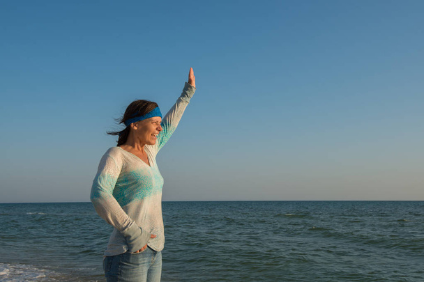 Sporty woman traveler stands alone on the sea coast - Fotografie, Obrázek