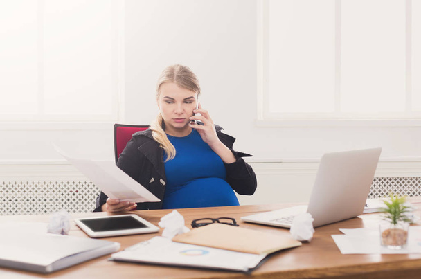 Вагітна бізнес-леді розмовляє по телефону в офісі
 - Фото, зображення